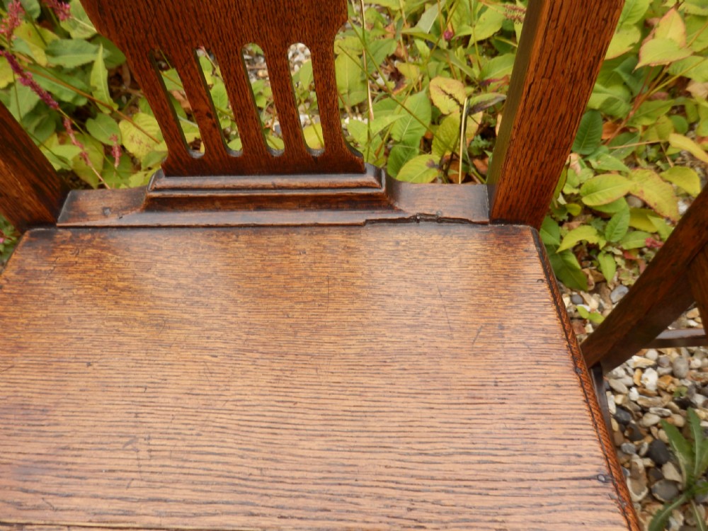 A set of six dark oak Georgian dining chairs featuring pierced vertical back splats, solid wooden seats, and straight legs connected by stretchers. View VIII