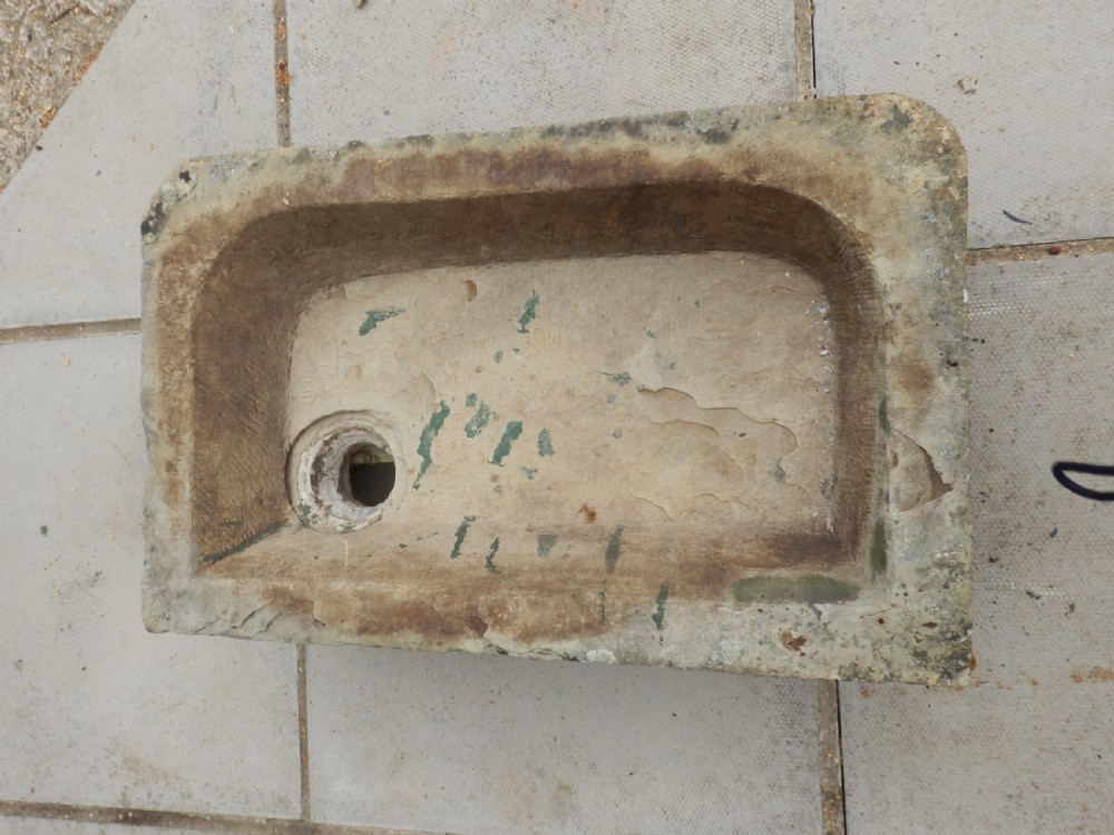 A rectangular, hand-carved antique stone sink displaying a textured exterior, weathered patina, and a corner drainage hole. View II