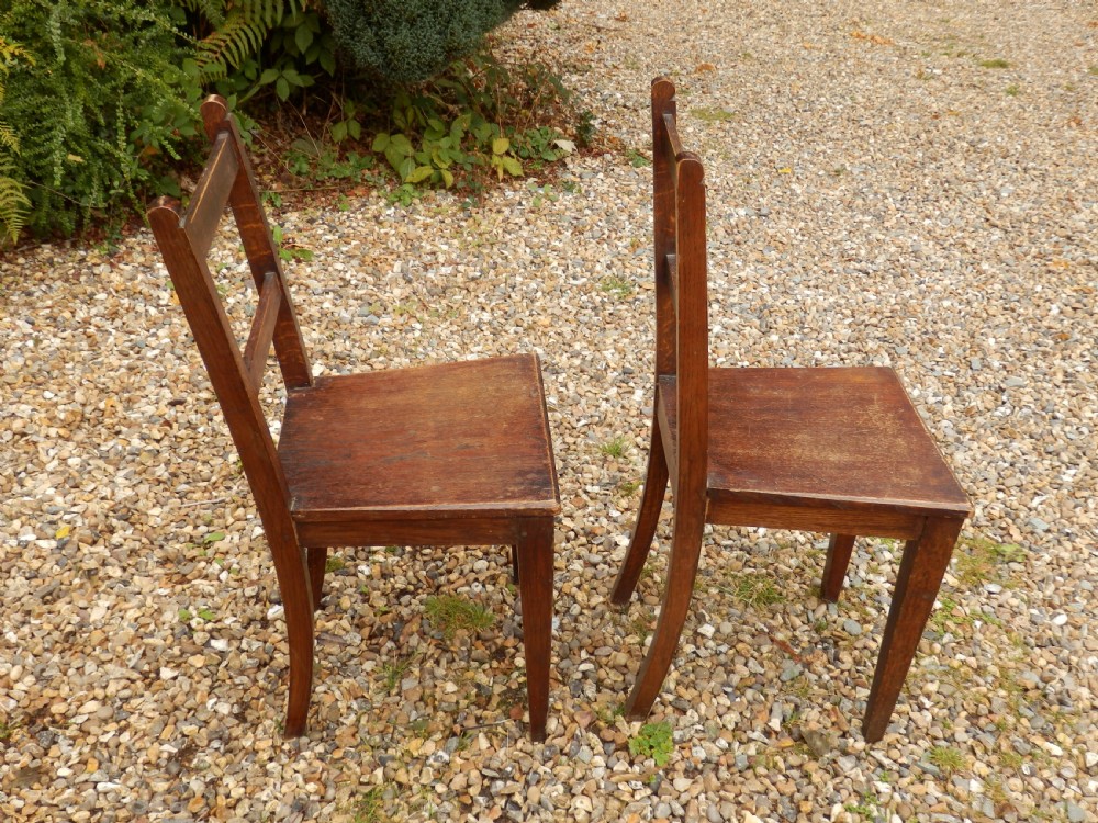 A pair of antique dark oak dining chairs with flat horizontal back slats, solid wood seats, and straight legs. View III