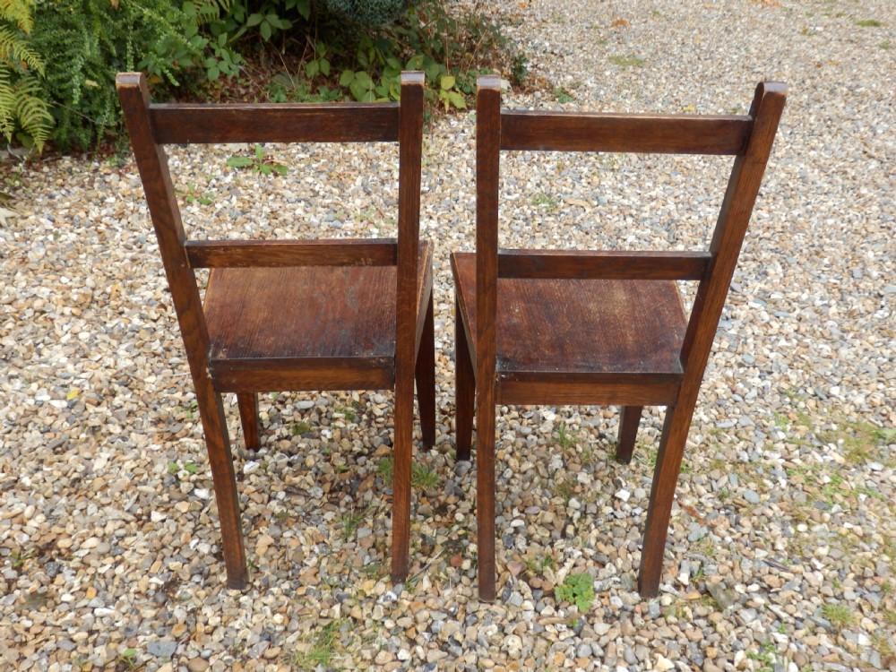 A pair of antique dark oak dining chairs with flat horizontal back slats, solid wood seats, and straight legs. View IV