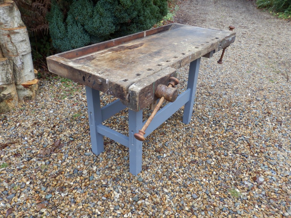 An antique wooden carpenters workbench featuring a thick weathered timber top with integrated vices on a painted grey base. View IV