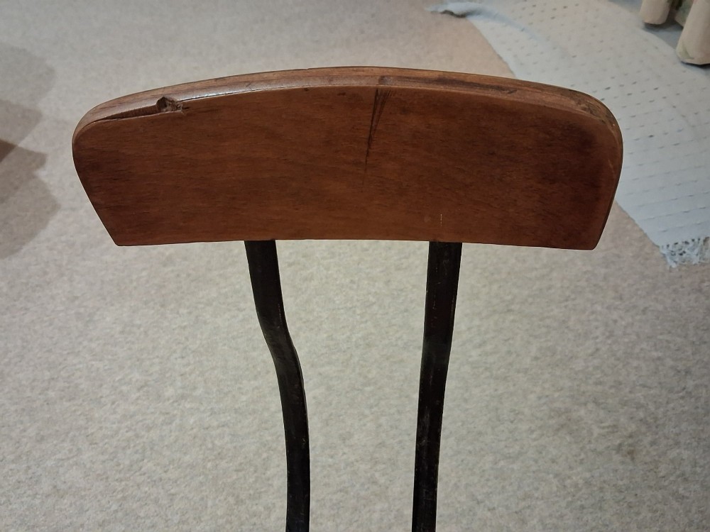An antique Singer machinist stool featuring a black cast iron four-legged base, a round wooden seat, and a curved wooden backrest. View IX