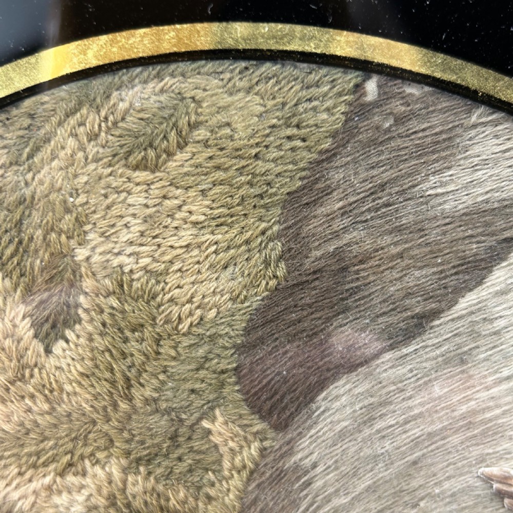 An oval Georgian silk embroidery depicting a seated woman and child within a landscape, featuring painted paper faces and set in a black frame. View XIV