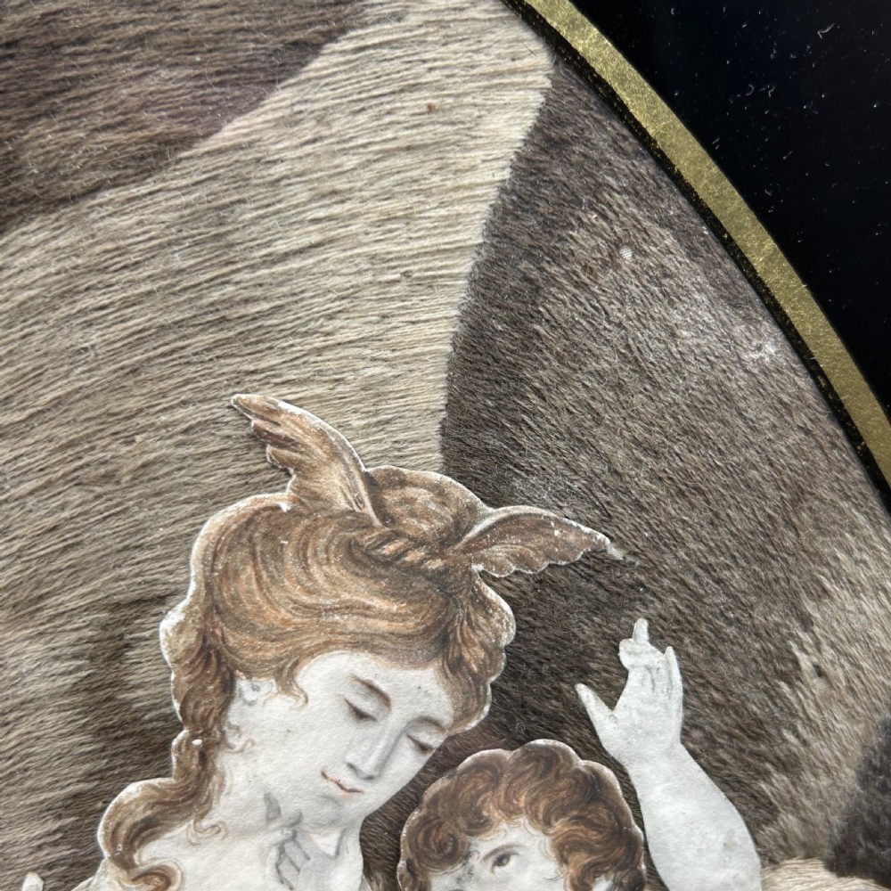 An oval Georgian silk embroidery depicting a seated woman and child within a landscape, featuring painted paper faces and set in a black frame. View XVIII