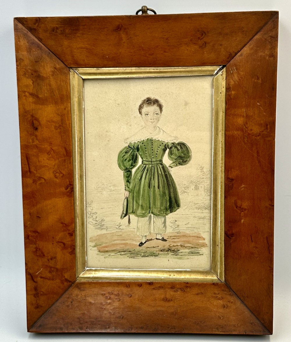 An antique watercolour portrait of a child wearing a green dress framed in figured maple wood with a gilded inner rim.