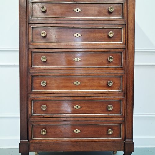 fig 1. An antique French mahogany semainier tallboy featuring seven drawers with round brass pulls and diamond-shaped brass escutcheons set on short turned feet.
