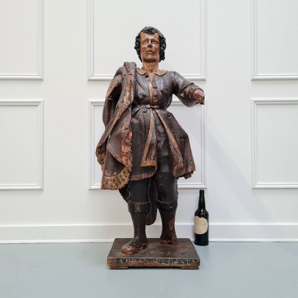 Full-length carved wood polychrome figure of a standing man in 17th-century attire on an inscribed rectangular base. View II