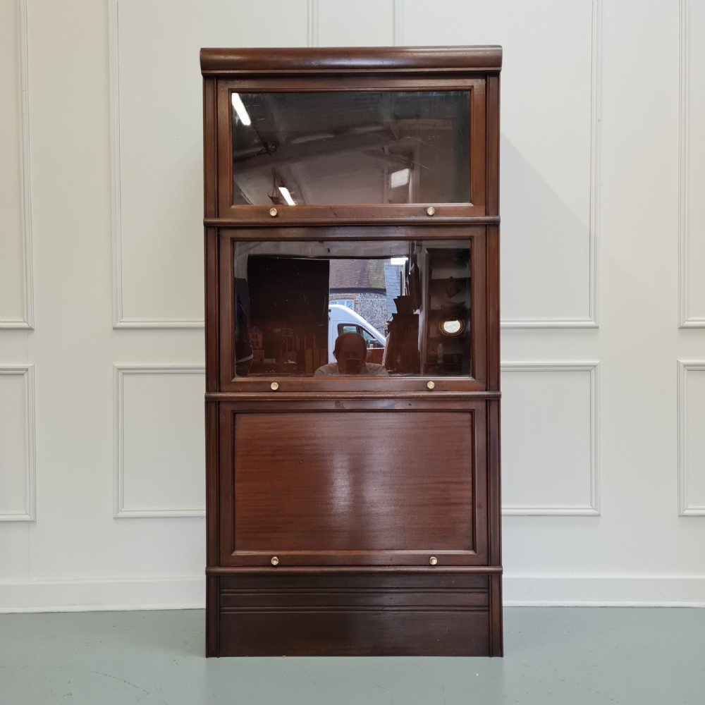 A tall dark mahogany 1930s French stacking haberdashery bookcase featuring two upper glazed compartments above a solid timber lower section.