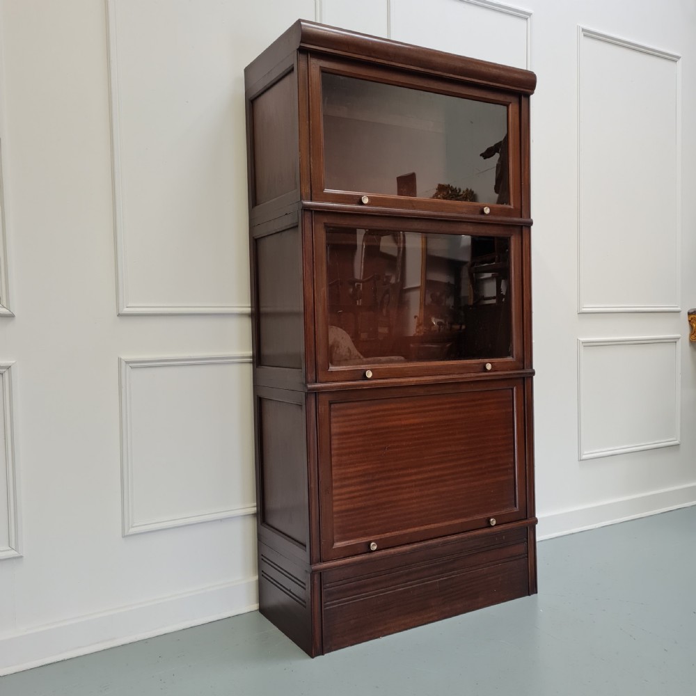 A tall dark mahogany 1930s French stacking haberdashery bookcase featuring two upper glazed compartments above a solid timber lower section. View II