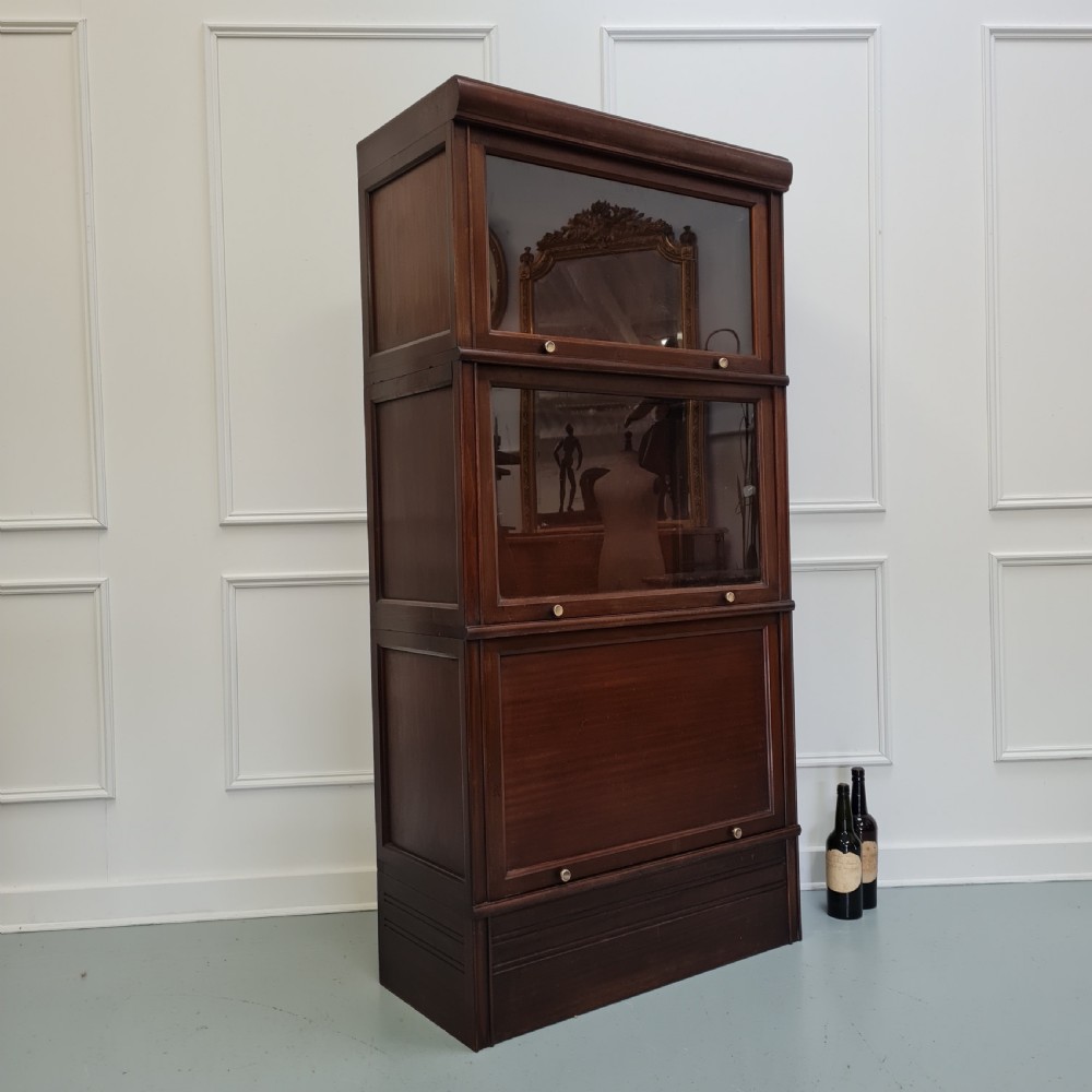 A tall dark mahogany 1930s French stacking haberdashery bookcase featuring two upper glazed compartments above a solid timber lower section. View V
