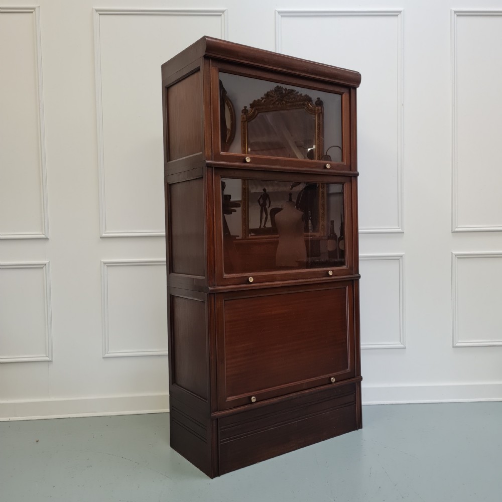 A tall dark mahogany 1930s French stacking haberdashery bookcase featuring two upper glazed compartments above a solid timber lower section. View VI