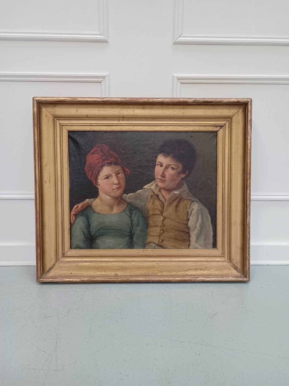 A Georgian era oil painting depicting two siblings in period attire within a moulded gold gilt frame.