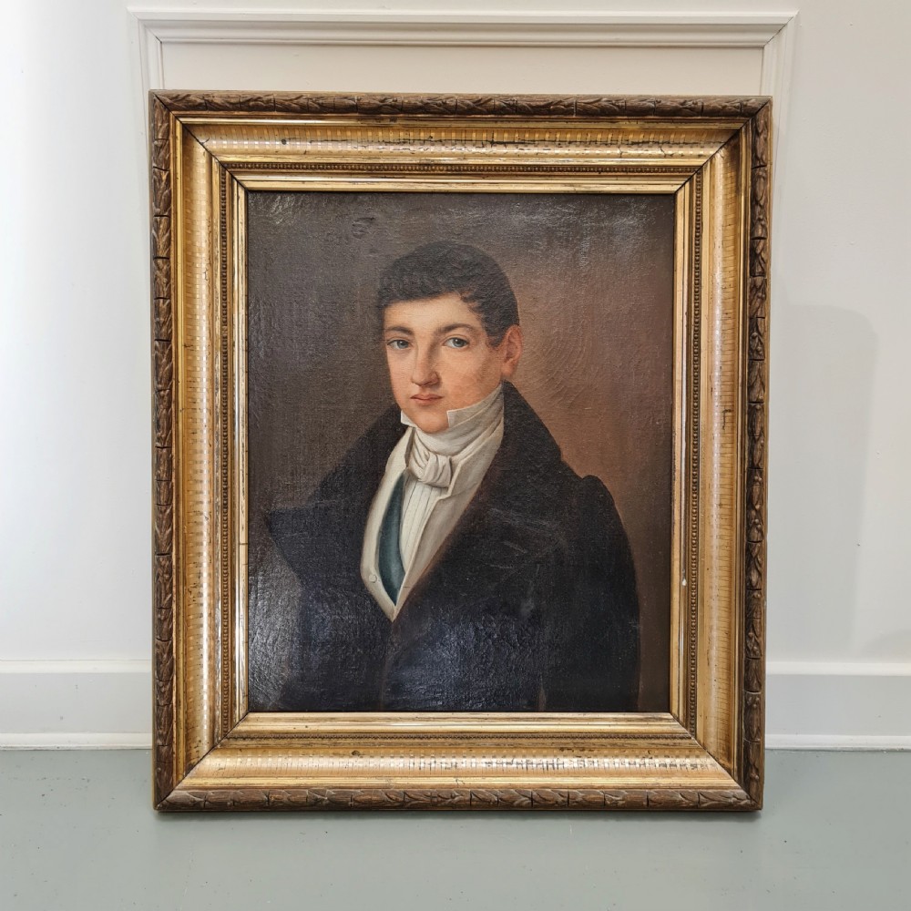 An antique oil portrait painting on canvas depicting a young male in 19th-century attire within an ornate gilded wooden frame.