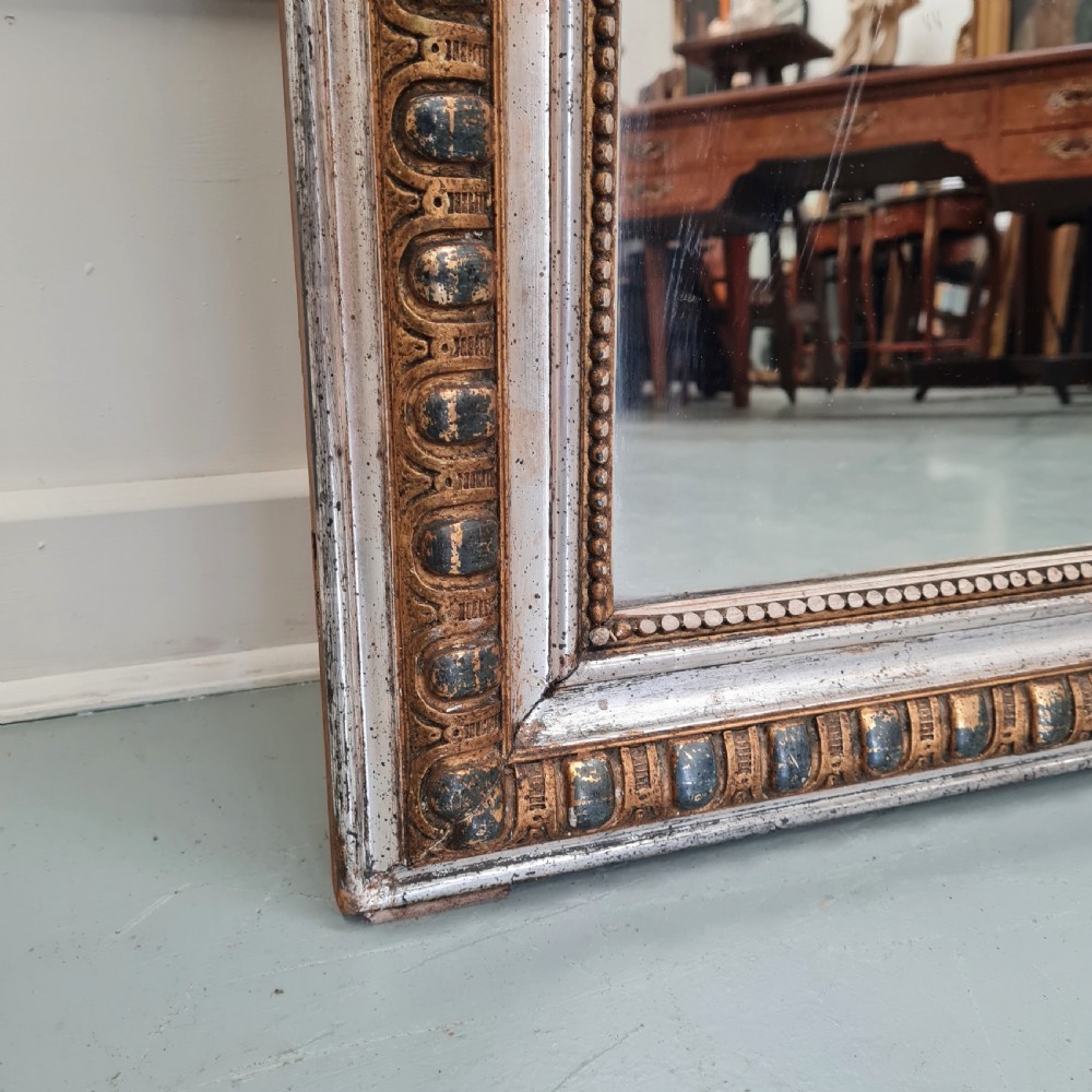 A large French antique mirror featuring a silver leaf frame with rounded upper corners and beaded moulding. View II