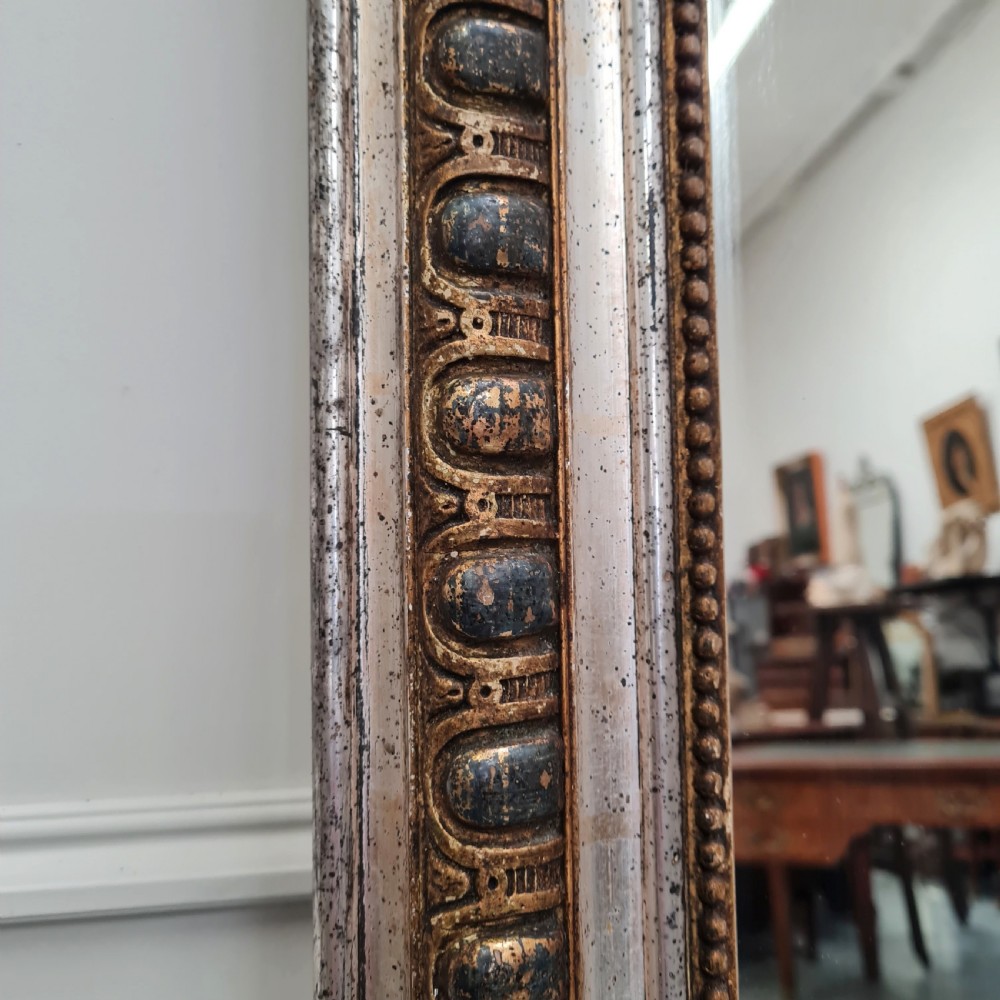 A large French antique mirror featuring a silver leaf frame with rounded upper corners and beaded moulding. View III