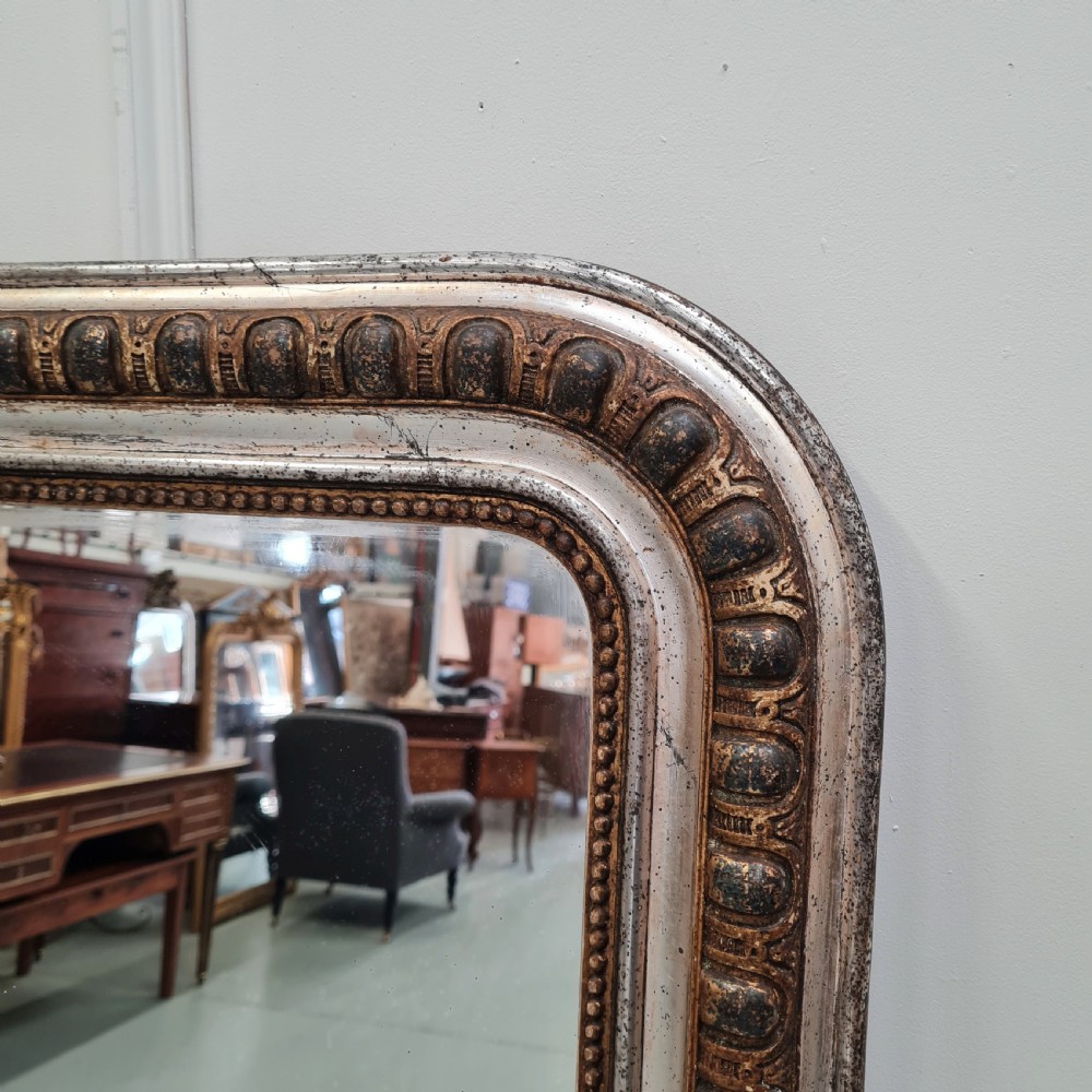 A large French antique mirror featuring a silver leaf frame with rounded upper corners and beaded moulding. View IV