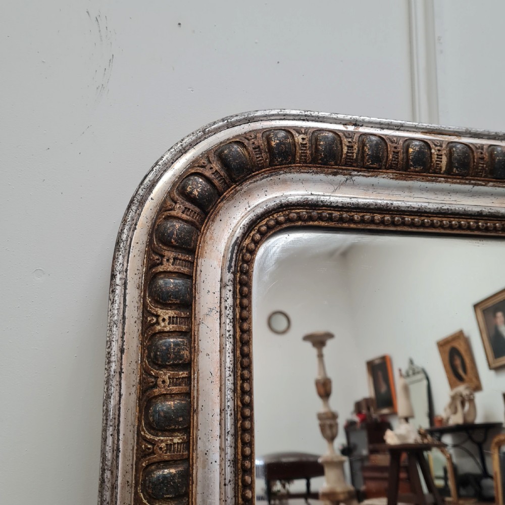 A large French antique mirror featuring a silver leaf frame with rounded upper corners and beaded moulding. View V
