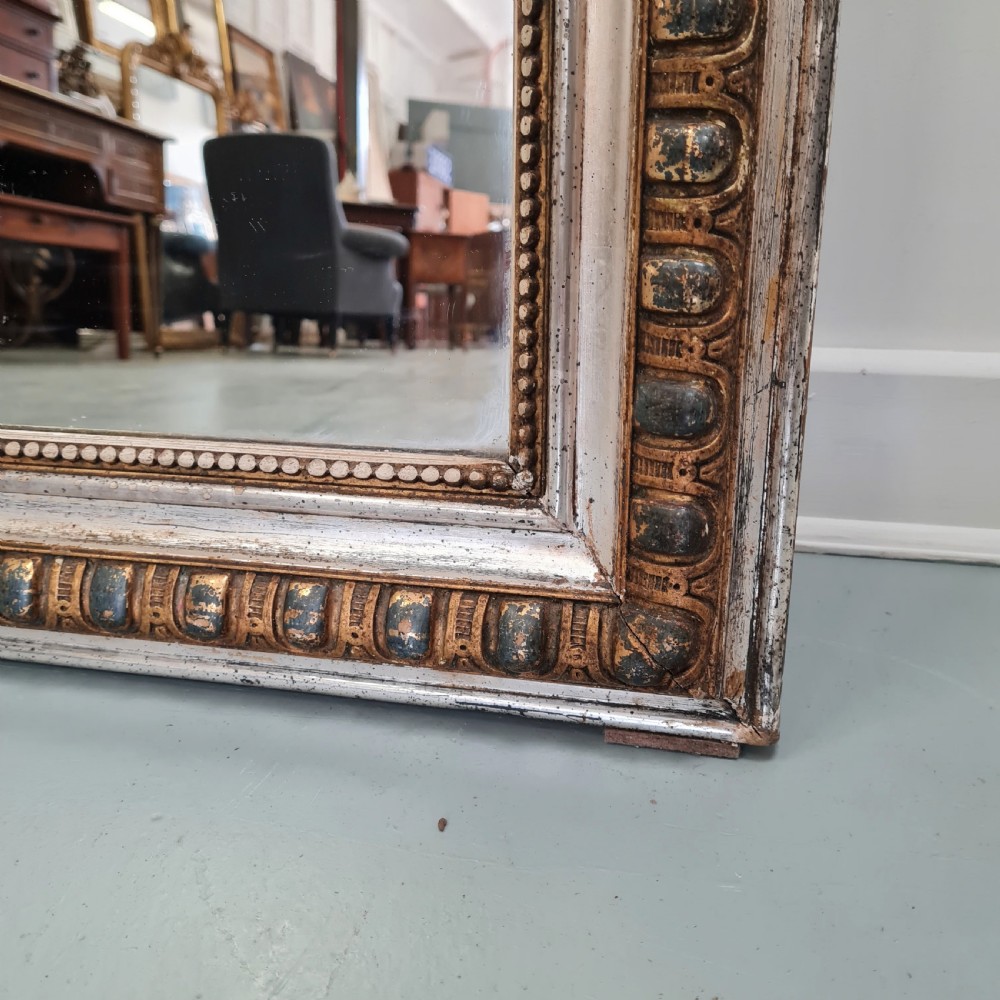 A large French antique mirror featuring a silver leaf frame with rounded upper corners and beaded moulding. View VI
