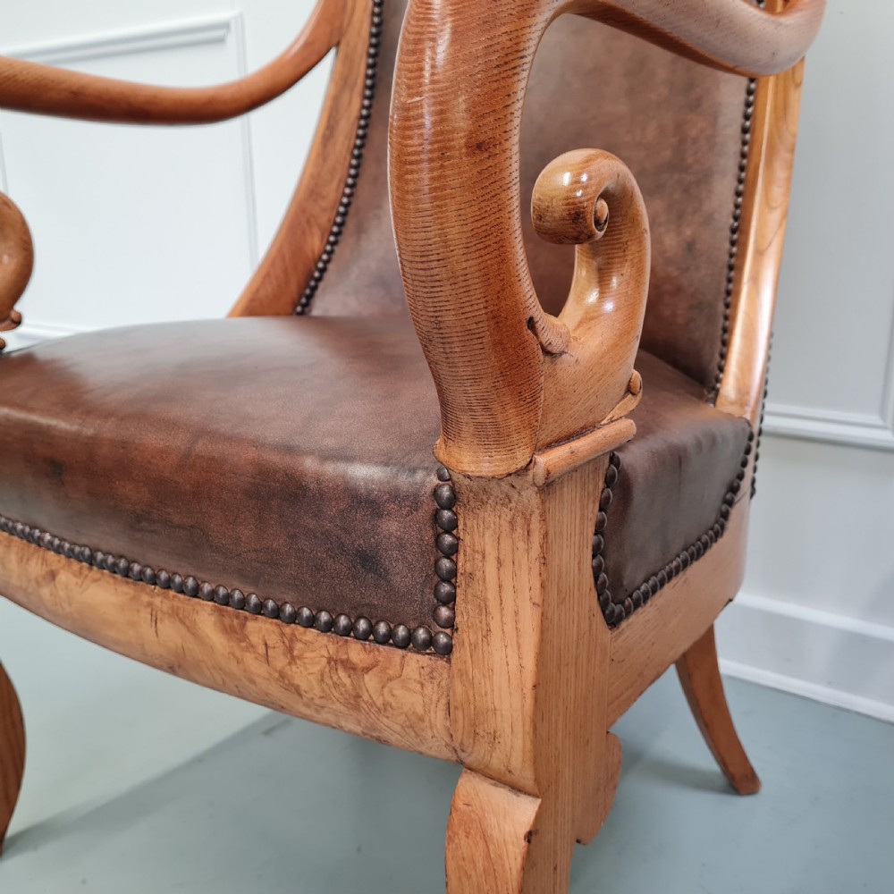 Pair of mid-19th-century ash wood armchairs featuring brown leather upholstery, stud detailing, and carved scrolled armrests. View VII