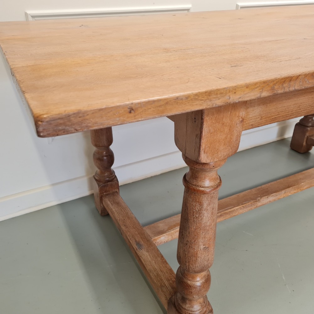 A late 19th-century oak refectory dining table featuring turned legs and a low rectangular stretcher base. View V