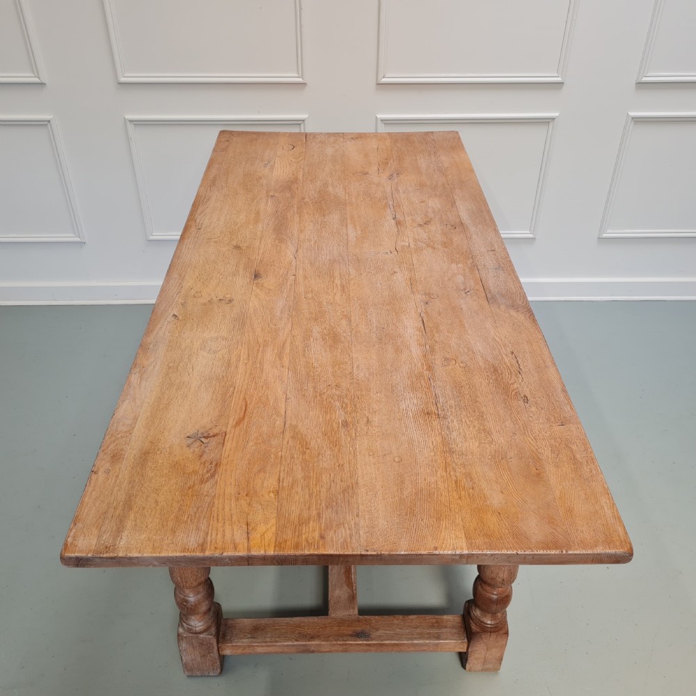 A late 19th-century oak refectory dining table featuring turned legs and a low rectangular stretcher base. View X