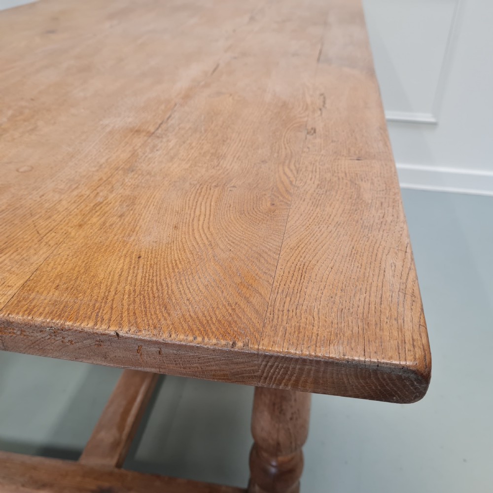 A late 19th-century oak refectory dining table featuring turned legs and a low rectangular stretcher base. View XI