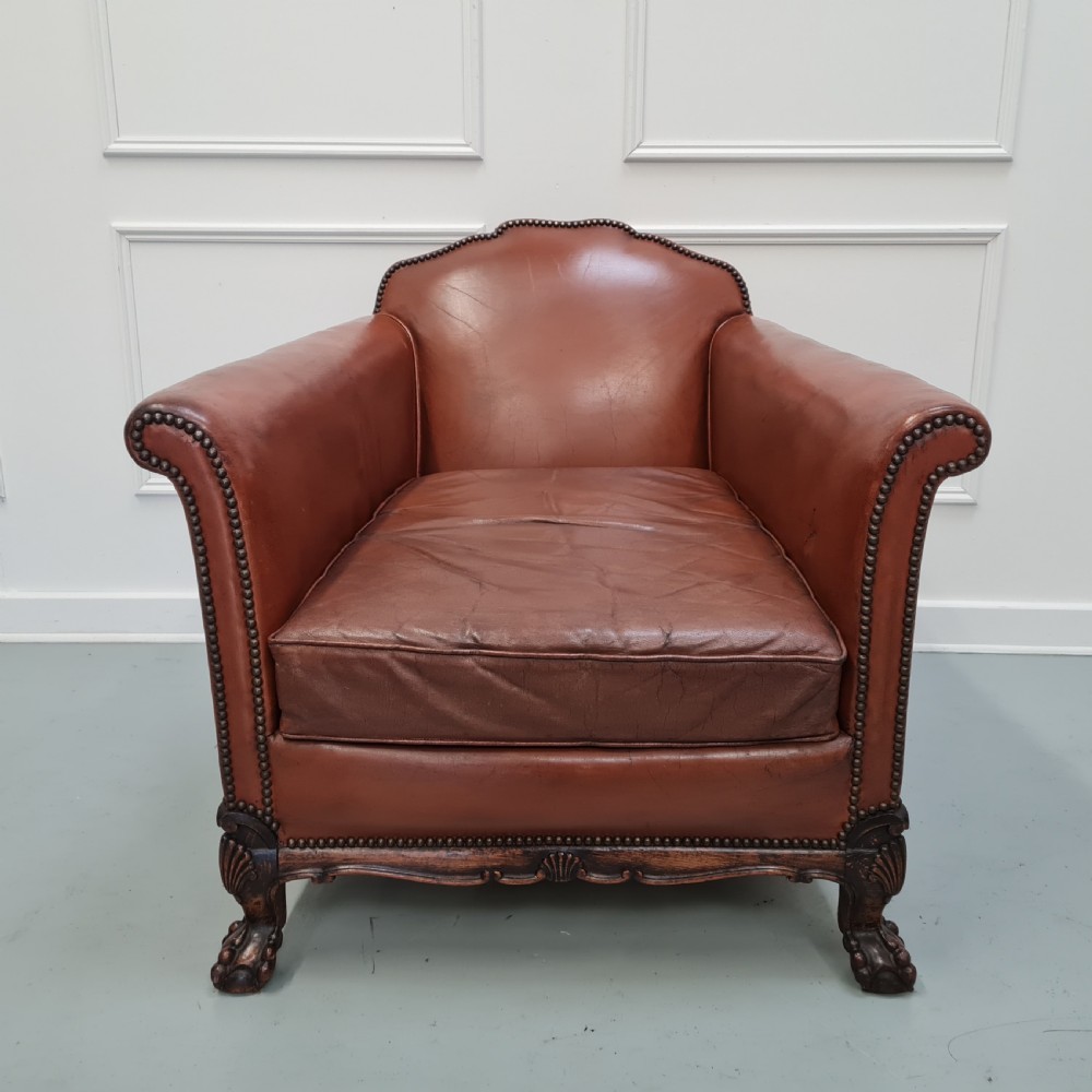 A 1930s brown leather armchair featuring brass studding trim and carved wooden feet. View II
