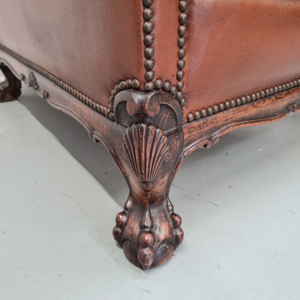 A 1930s brown leather armchair featuring brass studding trim and carved wooden feet. View III