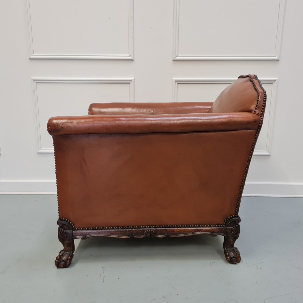 A 1930s brown leather armchair featuring brass studding trim and carved wooden feet. View IV