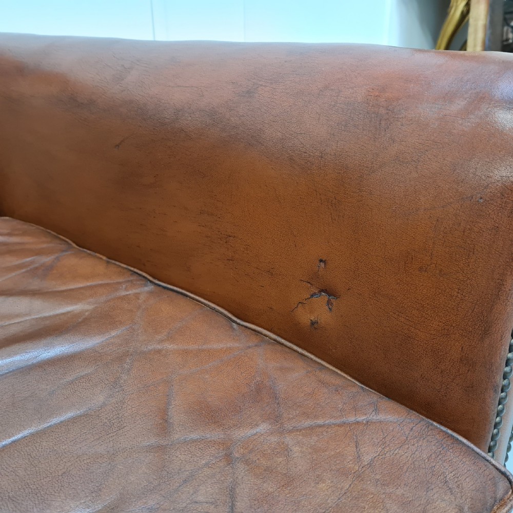 A 1930s brown leather armchair featuring brass studding trim and carved wooden feet. View V