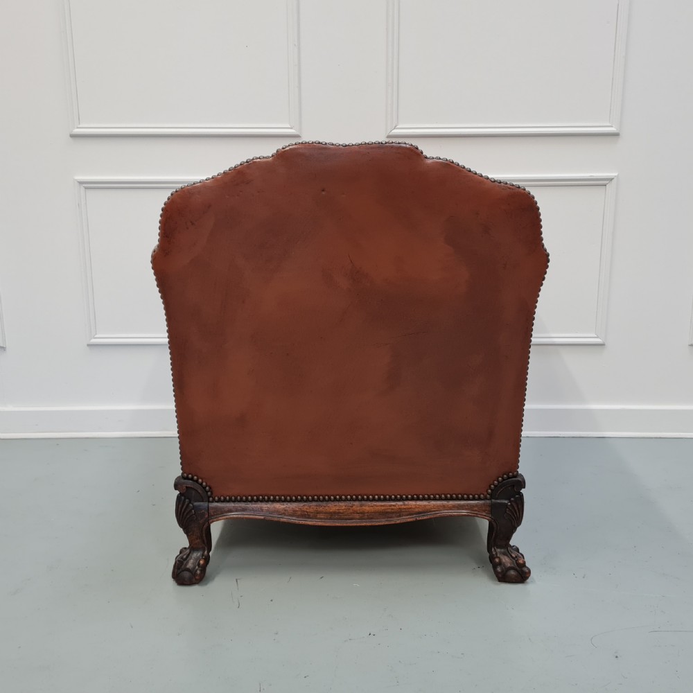 A 1930s brown leather armchair featuring brass studding trim and carved wooden feet. View VI