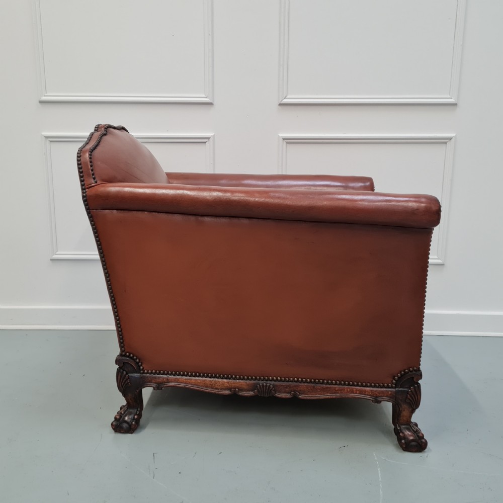 A 1930s brown leather armchair featuring brass studding trim and carved wooden feet. View VII