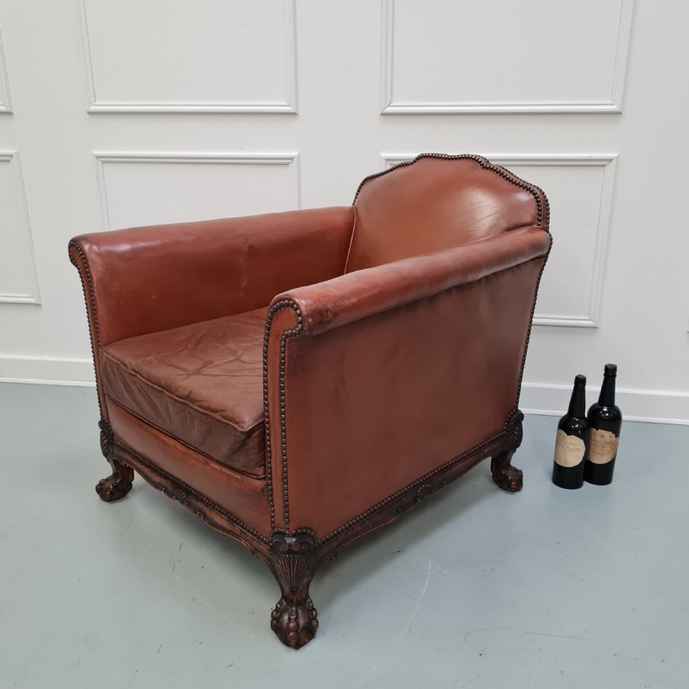 A 1930s brown leather armchair featuring brass studding trim and carved wooden feet. View VIII