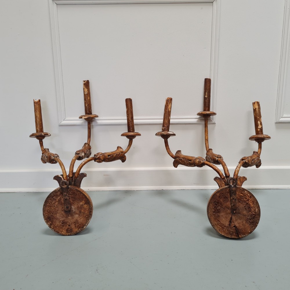 A pair of late 18th-century carved giltwood three-arm wall lights with foliate bases and slender curved arms. View IV