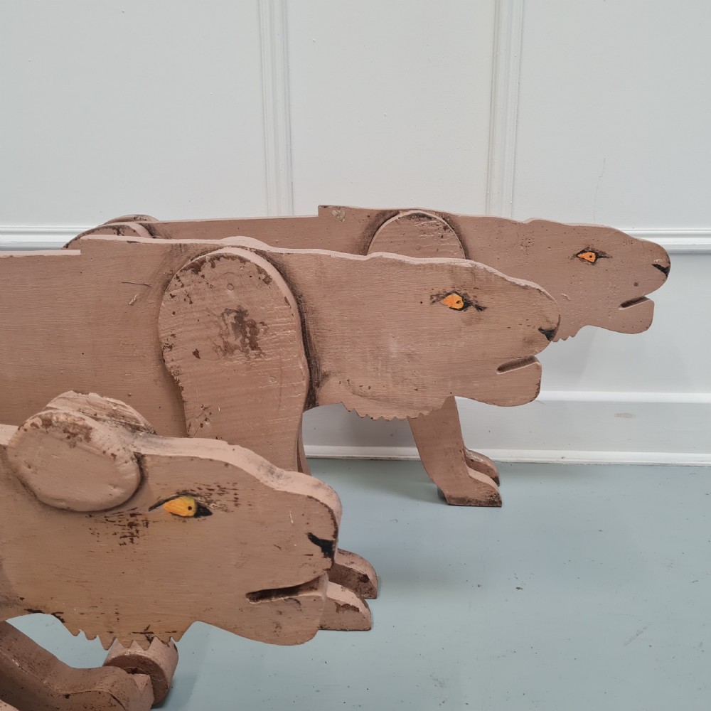 Three articulated painted wooden toy lionesses with small wheels resting on a light surface. View IV
