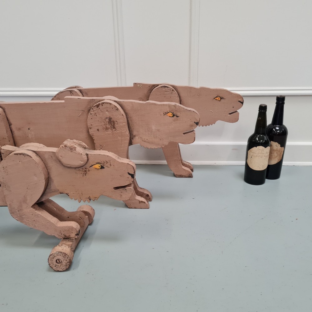 Three articulated painted wooden toy lionesses with small wheels resting on a light surface. View V