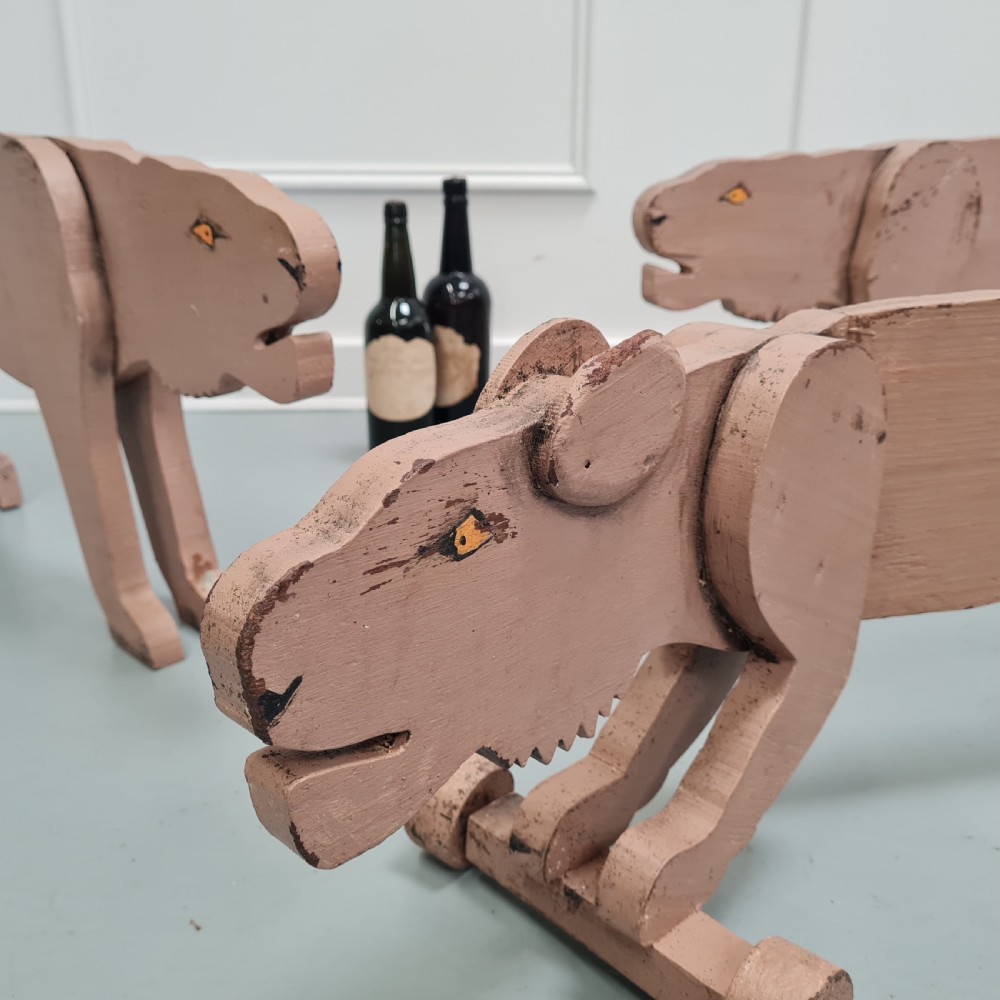 Three articulated painted wooden toy lionesses with small wheels resting on a light surface. View VIII