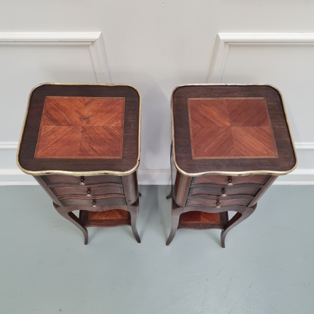 A pair of tall French kingwood bedside cabinets featuring three drawers, brass galleries, slender legs, and lower shelves. View II