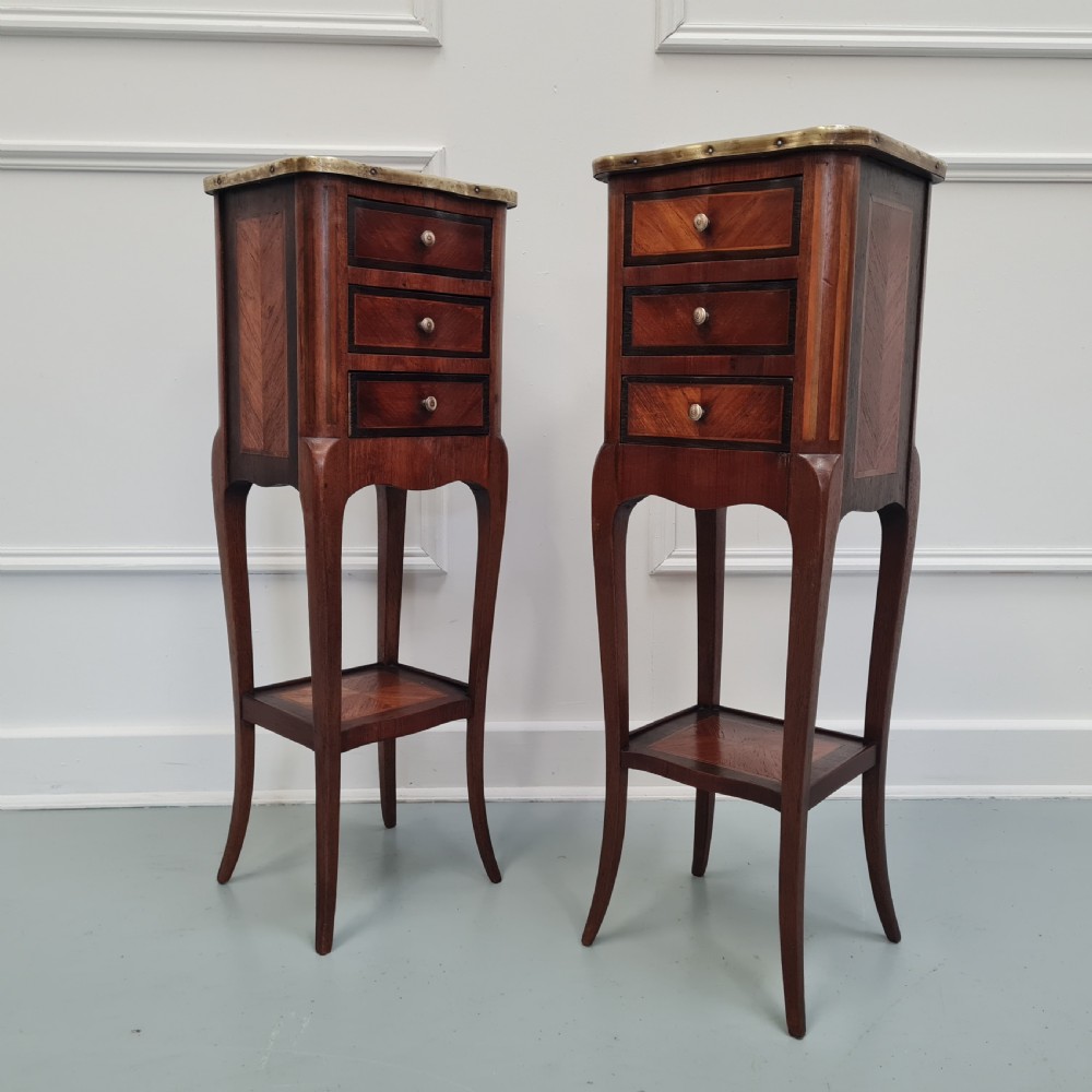 A pair of tall French kingwood bedside cabinets featuring three drawers, brass galleries, slender legs, and lower shelves. View III
