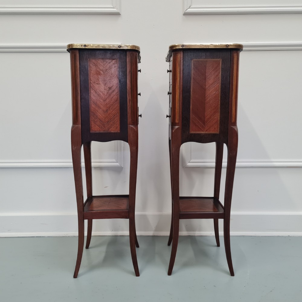 A pair of tall French kingwood bedside cabinets featuring three drawers, brass galleries, slender legs, and lower shelves. View VI
