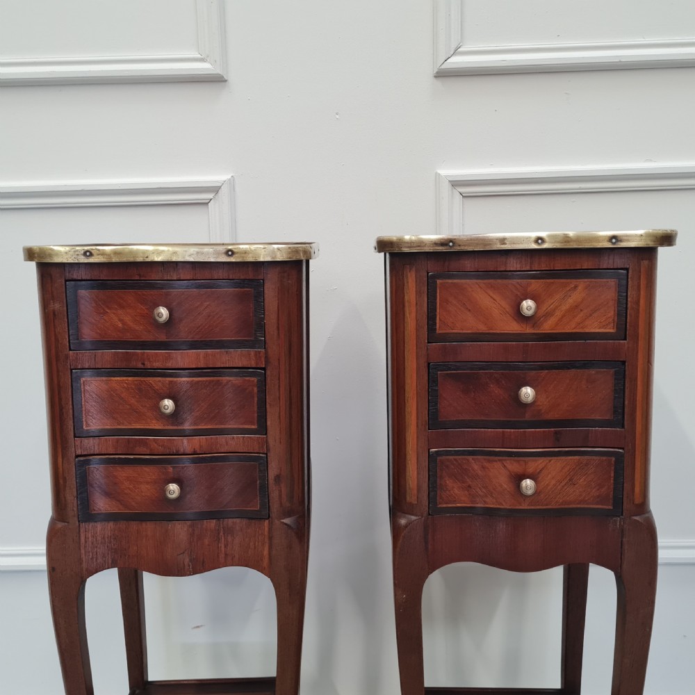 A pair of tall French kingwood bedside cabinets featuring three drawers, brass galleries, slender legs, and lower shelves. View VIII