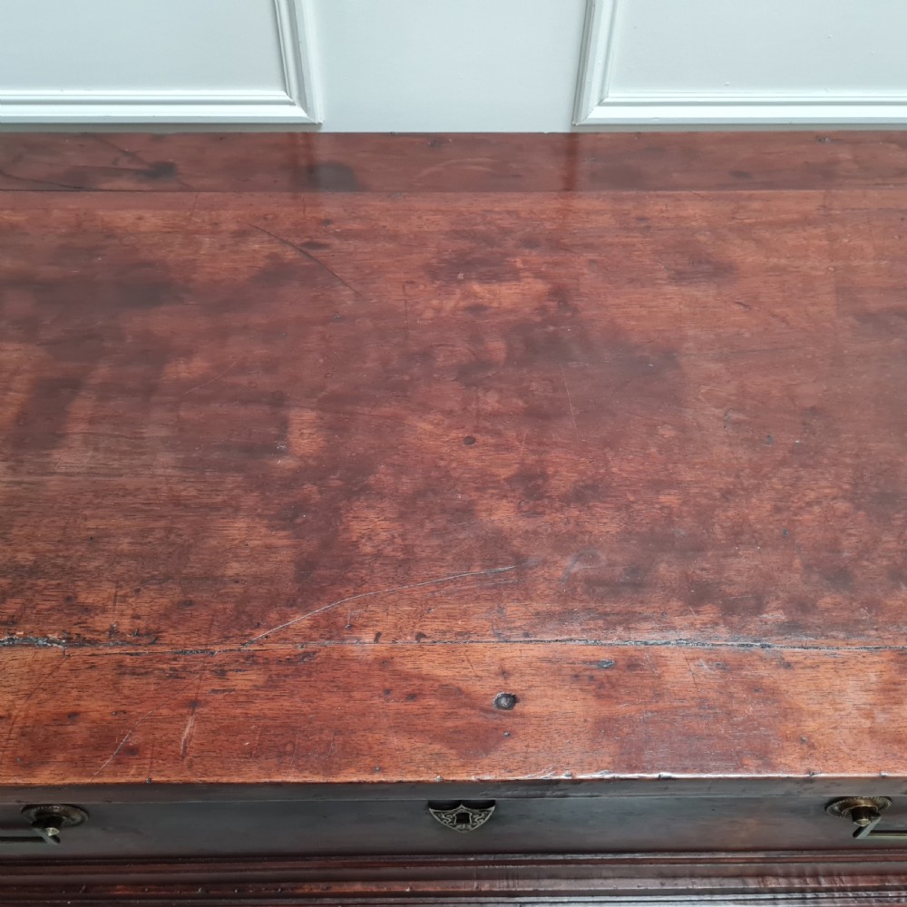 An early antique French cherry commode featuring three long drawers with brass drop handles and escutcheons. View V