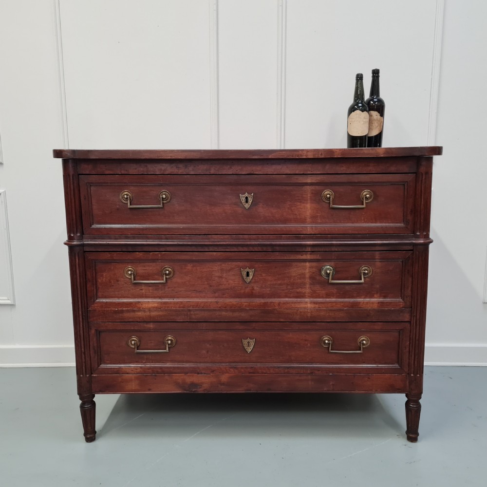 An early antique French cherry commode featuring three long drawers with brass drop handles and escutcheons. View VIII