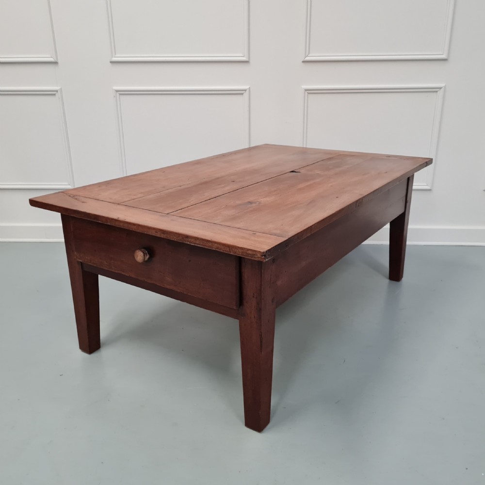 A mid-19th-century rectangular cherry wood coffee table featuring a single end drawer with a wooden knob and square tapered legs.