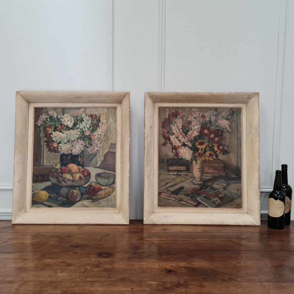 A pair of framed 1930s oil paintings depicting floral arrangements and fruit still life compositions in cream painted wooden frames. View VI