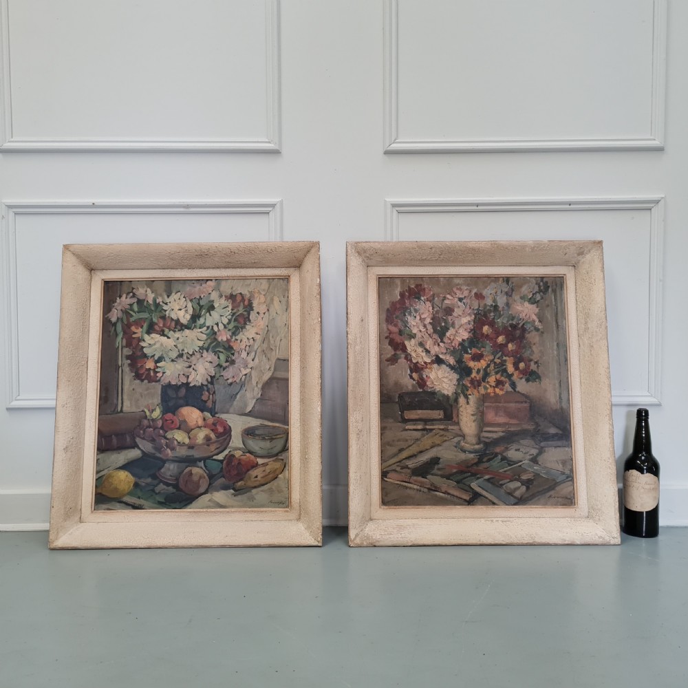 A pair of framed 1930s oil paintings depicting floral arrangements and fruit still life compositions in cream painted wooden frames. View VIII
