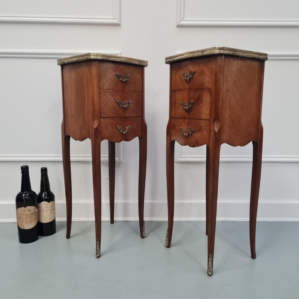 A pair of tall French kingwood bedside cabinets featuring three drawers, brass handles, cabriole legs, and top brass gallery rims. View VI