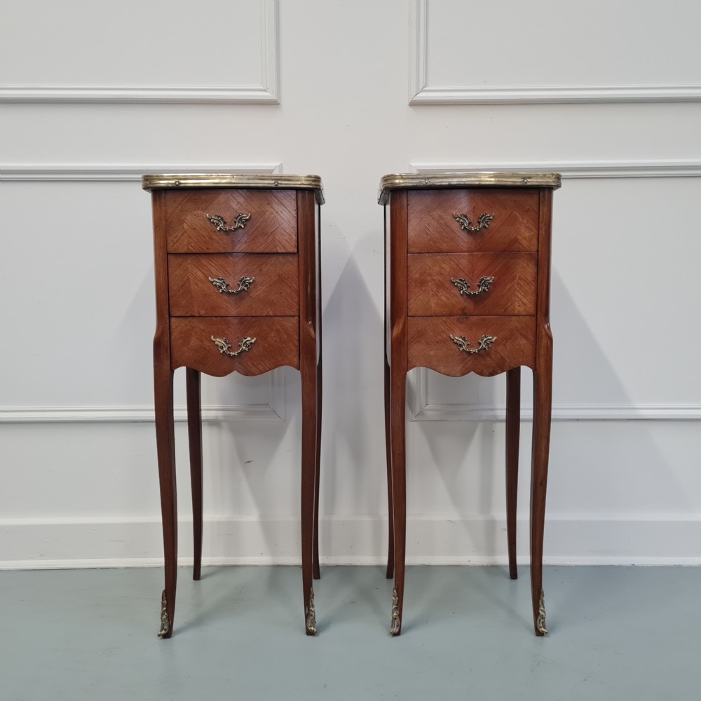 A pair of tall French kingwood bedside cabinets featuring three drawers, brass handles, cabriole legs, and top brass gallery rims.