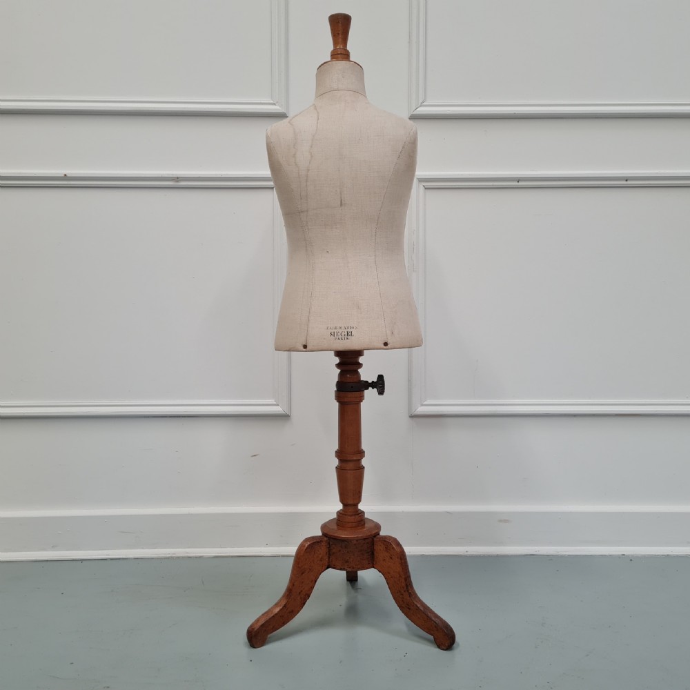 An antique French child-sized tailor mannequin by Stockman featuring a beige linen torso mounted on a turned wooden tripod stand. View II
