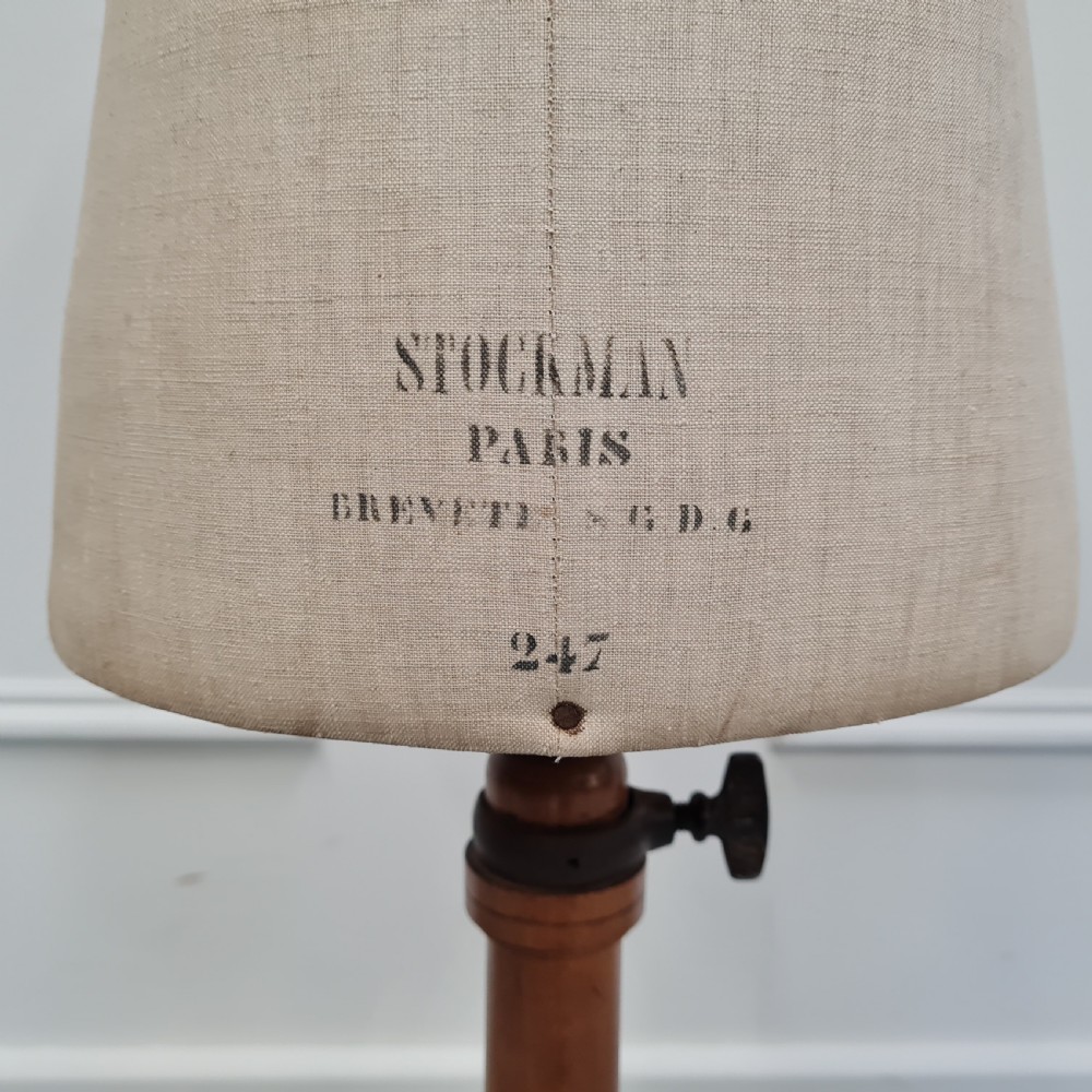 An antique French child-sized tailor mannequin by Stockman featuring a beige linen torso mounted on a turned wooden tripod stand. View IV